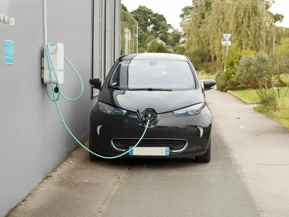Véhicule électrique noir Renault en cours de recharge sur voie résidentielle