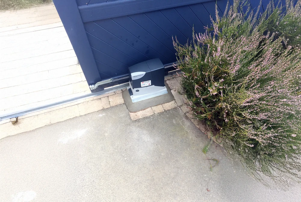 Scène extérieure résidentielle avec portail automatique coulissant bleu foncé partiellement ouvert