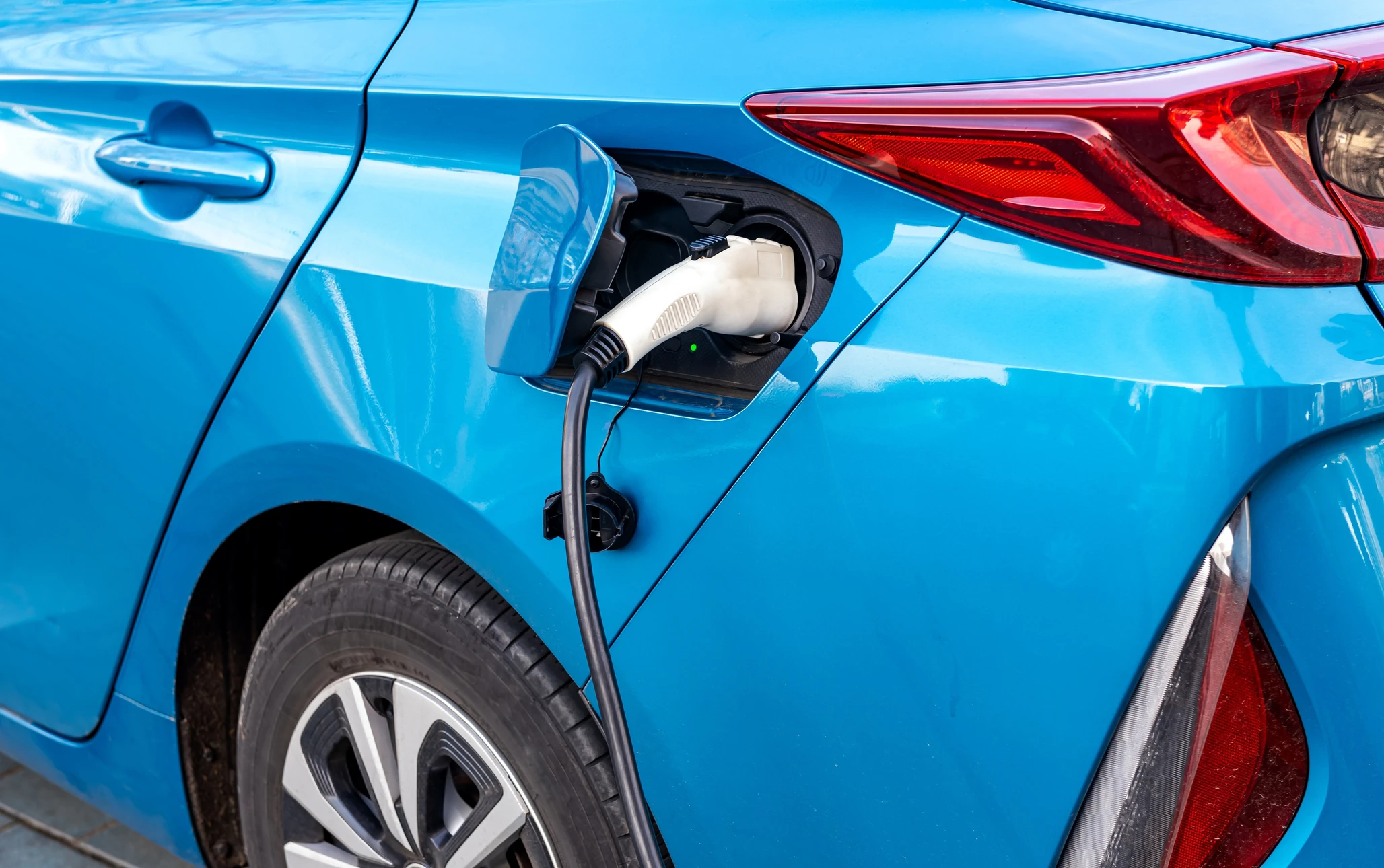Extérieur jour, véhicule électrique bleu en cours de recharge