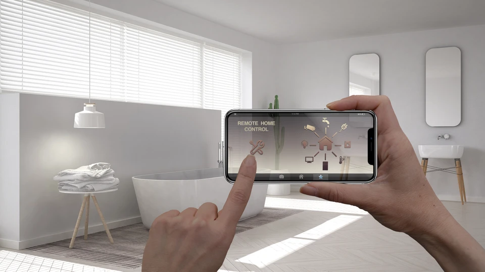 Main tenant un smartphone dans un intérieur moderne flou, interface holographique de domotique projetée
