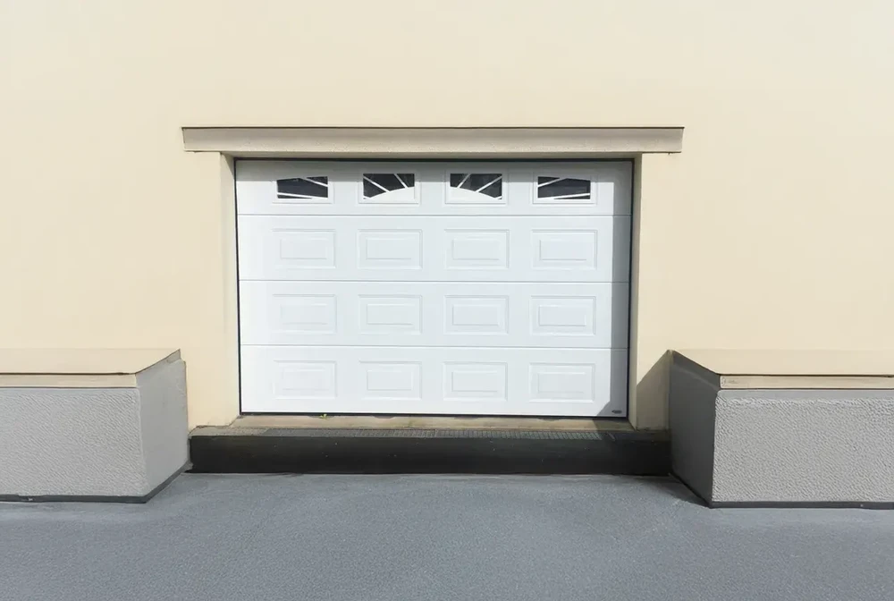 Porte de garage sectionnelle blanche avec fenêtres rectangulaires dans façade résidentielle beige